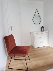 a red chair in a room with a dresser at Apartament Okrzei in Kłodzko