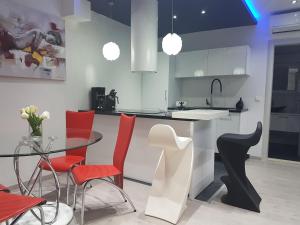 cocina con mesa de cristal y sillas rojas en Palladium City Center Apartments, en Makarska