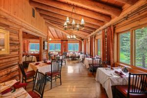 a dining room with tables and chairs and windows at Jenny Lake Lodge in Beaver Creek