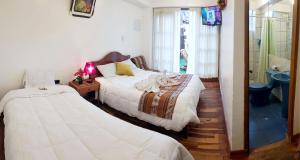 1 dormitorio con 2 camas y ducha en Hostal Comarca Imperial, en Cusco
