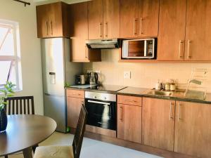 a kitchen with wooden cabinets and a table and a sink at Kilkenny Cottages 2 bedroom unit in Johannesburg