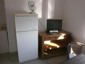 a white refrigerator next to a desk with a television at APARTMANI LAŠTRO in Jesenice