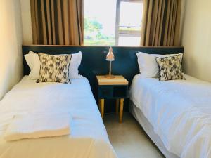 1 dormitorio con 2 camas y mesa con lámpara en Kilkenny Cottages 2 bedroom unit, en Johannesburgo