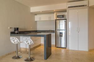 a kitchen with a counter with two stools and a refrigerator at Hotelito del Mar Playa del Carmen in Playa del Carmen