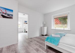 a white bedroom with a bed and a window at Apartament przy Bulwarze in Gdynia