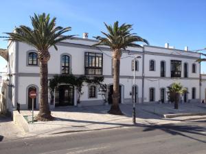 a white building with palm trees in front of it at Darcilla Guest House in Tarifa