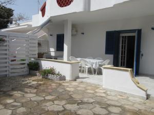 Cette maison blanche dispose d'une terrasse avec une table et des chaises. dans l'établissement Villa Oltremare, à Punta Prosciutto