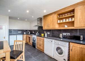 una cucina con armadi in legno, lavatrice e asciugatrice di Mallard Cottage a Whitehead Altre 15 foto