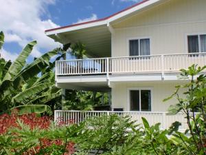 ein weißes Haus mit einem Balkon und einigen Pflanzen in der Unterkunft Bears' Place Guest House in Kailua-Kona