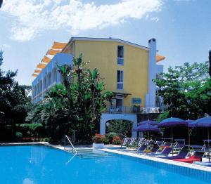 a swimming pool with chairs and a building at Hotel San Giovanni Terme in Ischia