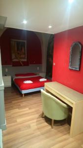 a bedroom with a red wall with a bed and a desk at Hotel de Savoie in Annecy