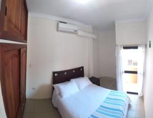 a bedroom with a white bed and a window at Hostal Duncan in Puerto Ayora
