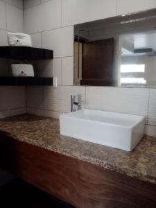 y baño con lavabo blanco y espejo. en HOTEL AZTECA INN, en Ensenada