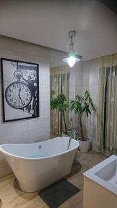 a bath tub in a bathroom with a clock on the wall at Apartament Loft 100 m2 Centrum Bydgoszcz in Bydgoszcz