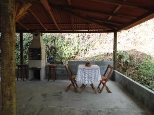 a table and chairs on a porch with a stove at Chalé Linda Vista 5 min. do Centro in Nova Friburgo