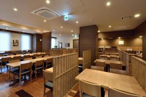 Hotel Route-Inn Shin-Shirakawa Eki Higashi في شيراكاوا: غرفة طعام مع طاولات وكراسي خشبية