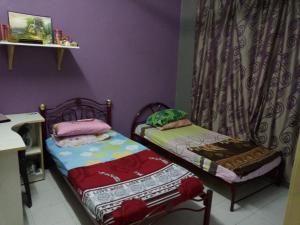 - 2 lits jumeaux dans une chambre aux murs violets dans l'établissement GERIK BANDING HOMESTAY, à Gerik
