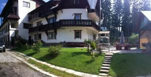 a large white house with a lawn in front of it at Pensiunea Margaritar in Predeal