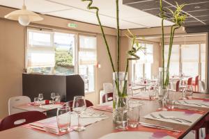 une salle à manger avec des tables, des verres et des vases dans l'établissement Campanile Poitiers, à Poitiers