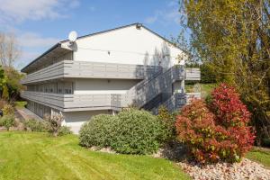 a white house with a balcony and some bushes at Campanile NATURE - Poitiers Sud Aeroport in Poitiers