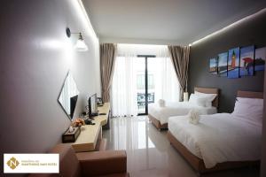 a hotel room with two beds and a television at Namthong Nan Hotel in Nan