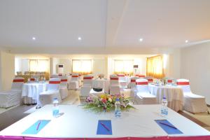 a banquet hall with white tables and white chairs at SRM Hotel in Tuticorin