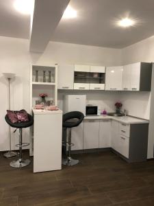 a kitchen with white cabinets and two bar stools at Villa Residence in Sînmartin