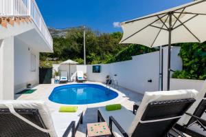 a patio with a pool and chairs and an umbrella at Apartments Orange Tree in Cavtat