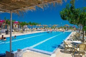 una piscina con sillas, mesas y sombrillas en Santorini Camping/Rooms, en Fira