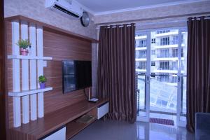 a living room with a television and a large window at Gateway Pasteur 2BR tower depan Ruby 7 C in Bandung