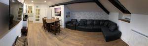 a living room with a black couch and a table at 3 Park View in Barmouth