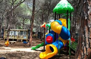 a playground in a park with a tree at Camping Bella Sardinia in S'archittu Cuglieri