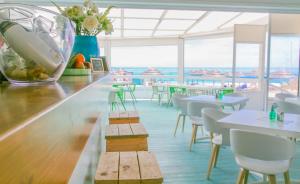 a restaurant with tables and white chairs and windows at Lovely Burgau villa just 3 mins walk from beach in Budens
