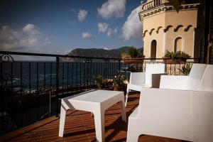 a balcony with white chairs and a building and the ocean at Camere Nicolina in Vernazza