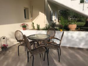 a glass table and four chairs on a patio at Armonia Apartment in Plataria