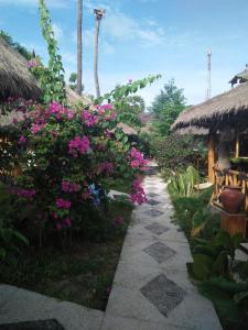 a garden with pink flowers and a pathway at Tua Tua Keladi Bungalows in Gili Air
