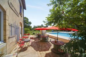 un patio con mesas y sillas junto a una piscina en La Gare aux Anes, en Combe-Redonde