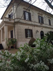 uma casa antiga com janelas pretas e flores brancas em B&B Villa Gualterio em Bolsena