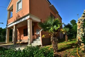 a house with a palm tree in front of it at Apartments Edita in Zadar