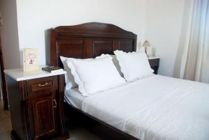 a bed with a wooden head board and white pillows at Eleni Apts in Kamilari