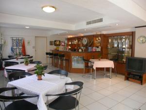 a restaurant with tables and chairs and a tv at Emily Hotel in Samos