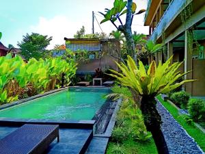une piscine au milieu d'un jardin dans l'établissement Uma Kutuh 2, à Ubud