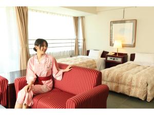 a woman sitting on a chair in a hotel room at Hotel Sunmi Club in Atami