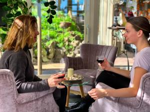 deux femmes assises sur des chaises avec des verres de vin dans l'établissement Mare Sanat, à Wijk aan Zee