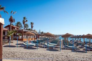 grupa leżaków i parasoli na plaży w obiekcie Apartamento Las Brisas w mieście Mijas