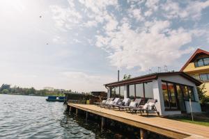 eine Anlegestelle mit Stühlen und ein Haus auf dem Wasser in der Unterkunft Hotel Inselhof in Malchow