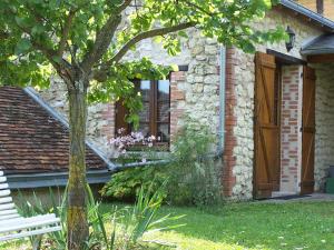 une maison avec un arbre et un banc devant elle dans l'établissement Gite Malivert, à Dierre