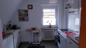 a kitchen with white cabinets and a window and a desk at Am Kanal in Neuhaus an der Oste