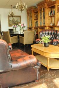 a living room with a leather couch and a table at de Brabantse Biesbosch in Werkendam