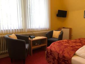 a hotel room with a bed and two chairs at Thermen Hotel Pension Villa Holstein in Bad Salzuflen